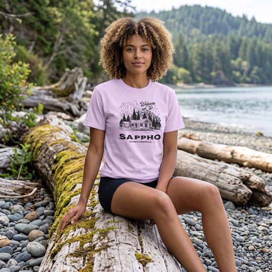 Adult model Zara wearing a retro-inspired mountain cabin tee in an outdoor setting with greenery, highlighting the vintage design and relaxed fit.