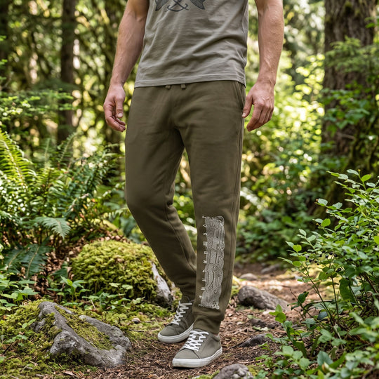 Ben showcasing comfortable forest-green fleece sweatpants with Viking serpent design in natural daylight outdoors.