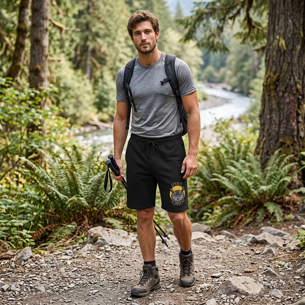 Outdoor scene with a man modeling Spirit Caller fleece shorts featuring owl design, greenery background, natural daylight, relaxed casual style.