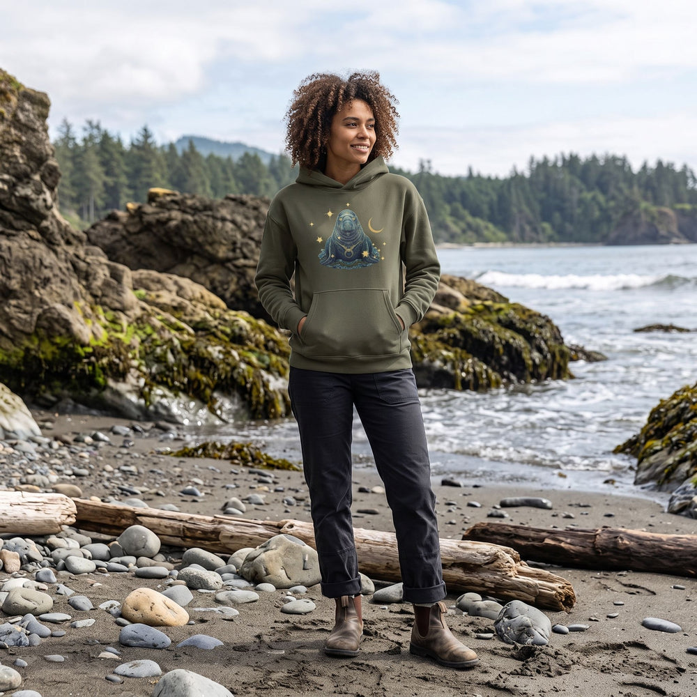 Outdoor scene with Zara modeling the Taurus Northern Elephant Seal Organic Fleece Hoodie in natural daylight, surrounded by greenery and natural elements.