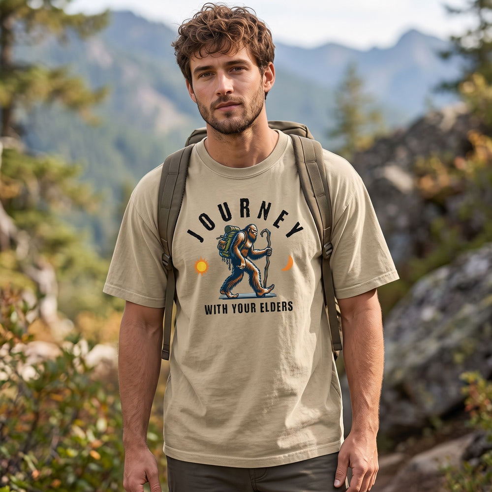 Casual male model wearing The Ancient Nomad tee in an outdoor setting with rocks and trees, emphasizing adventure-ready style.