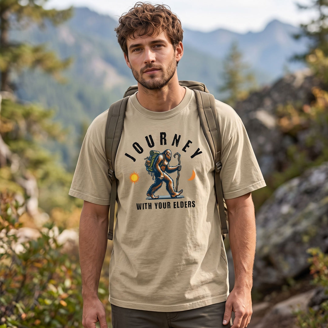 Casual male model wearing The Ancient Nomad tee in an outdoor setting with rocks and trees, emphasizing adventure-ready style.