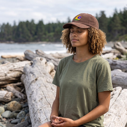 Outdoor scene featuring a model wearing the Forest Om Corduroy Meditation Cap in a natural setting with greenery, showcasing relaxed style and connection to nature.
