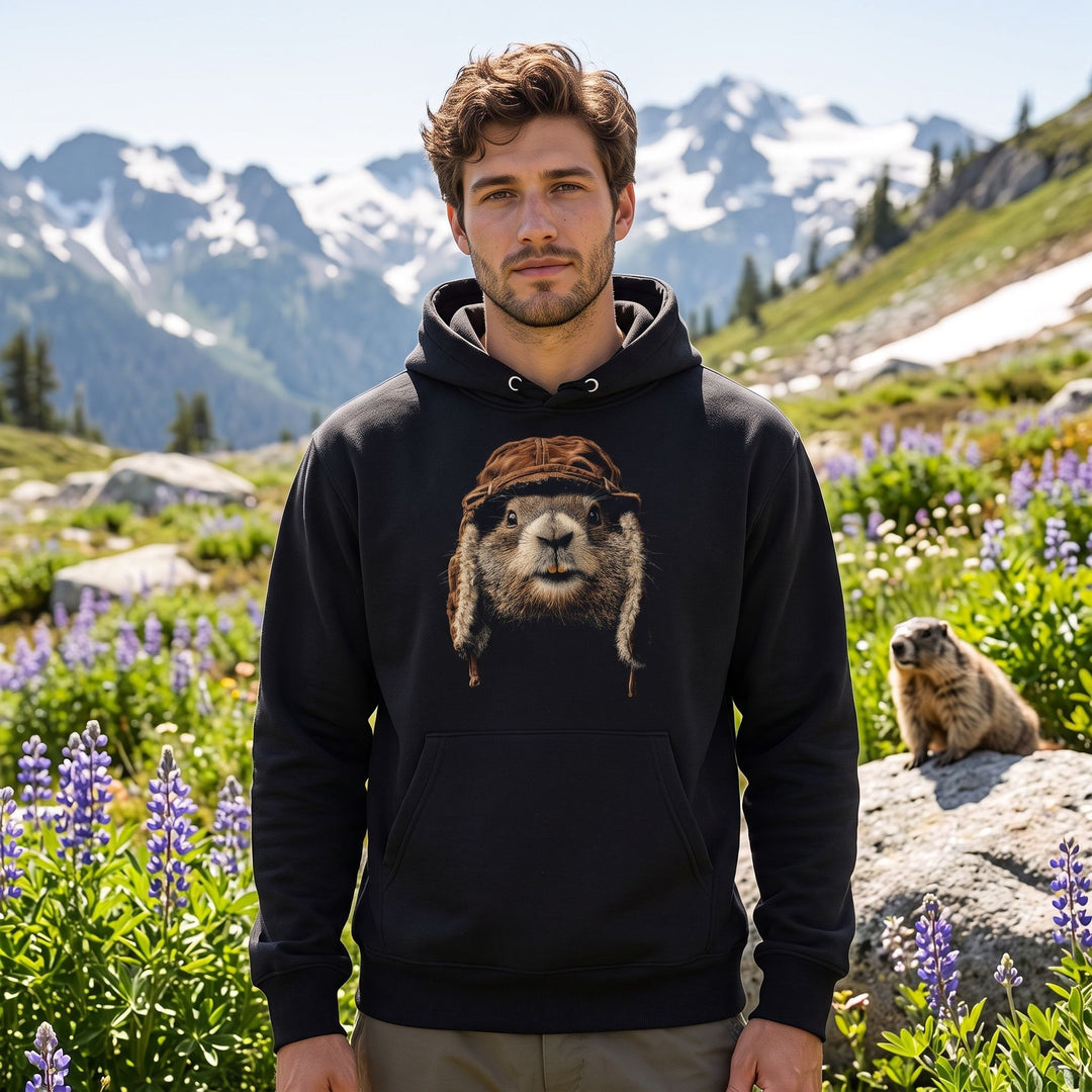 Adult model wearing The High-Country Local hoodie outdoors amid greenery with blurred foliage, showcasing the casual mountain-inspired design.