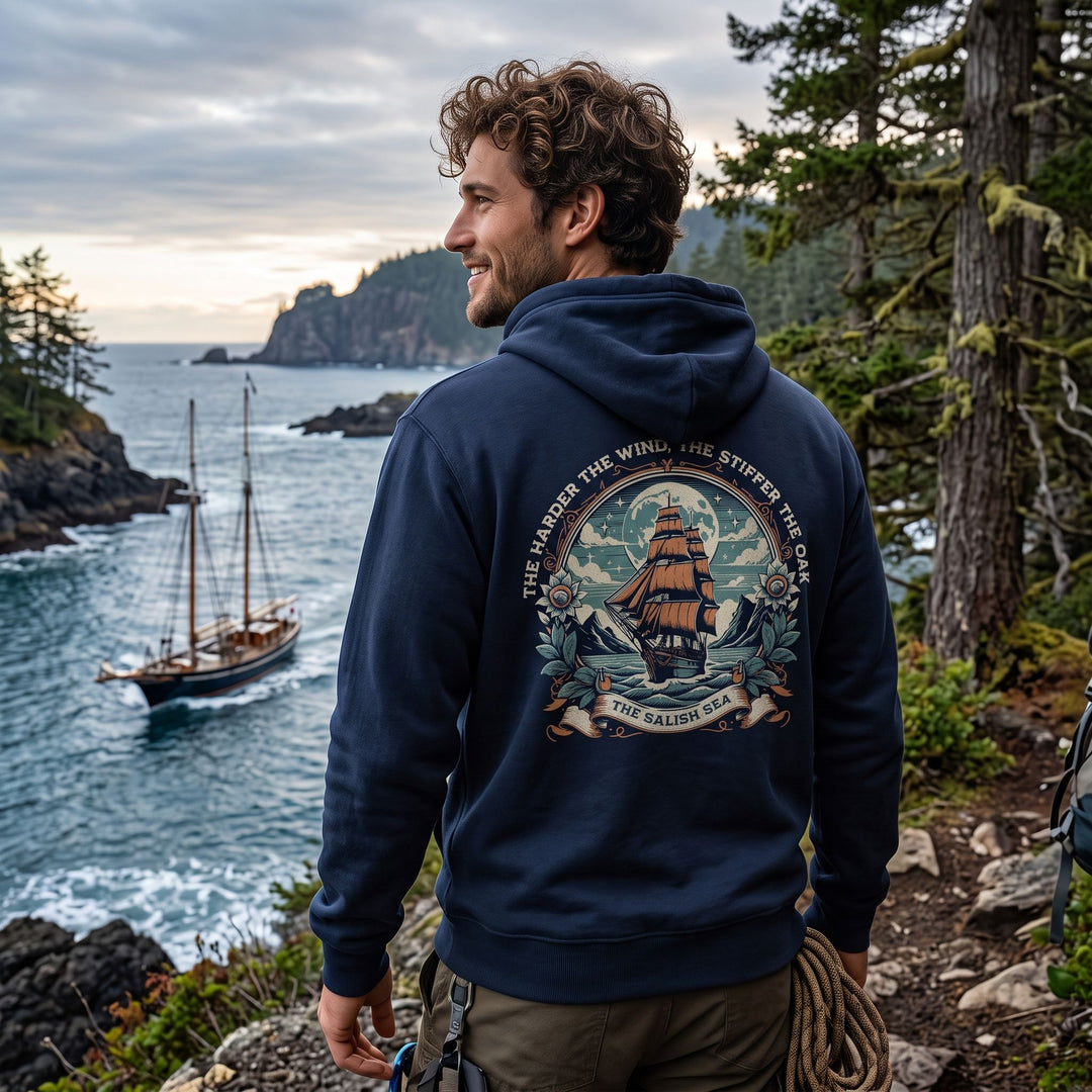 Casual male model wearing The Iron Oak Salish Sea Hoodie outdoors with greenery, showcasing the relaxed fit and durable design in natural daylight.