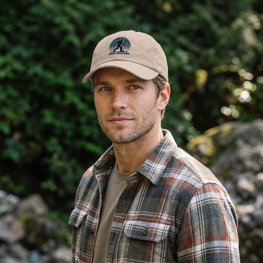 Casual outdoor scene with a model wearing a Tree Knocker Dad Hat featuring Sasquatch patch, set amidst greenery and natural daylight.